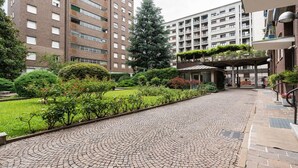 Ein Innenhof mit einem Kopfsteinpflasterweg, umgeben von Grünflächen und hohen Gebäuden.