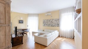 A living room with a sofa, a dining table, and a TV. - Ampio Trilocale in zona Solari - Mirable PM (Milano)