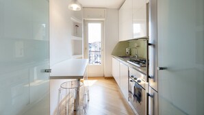 A modern kitchen with a white countertop, stainless steel appliances, and a glass door leading to a balcony. - Ampio Trilocale in zona Solari - Mirable PM (Milano)