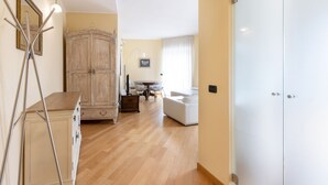 A hallway with a wooden cabinet, a white sofa, and a dining area with a table and chairs. - Ampio Trilocale in zona Solari - Mirable PM (Milano)
