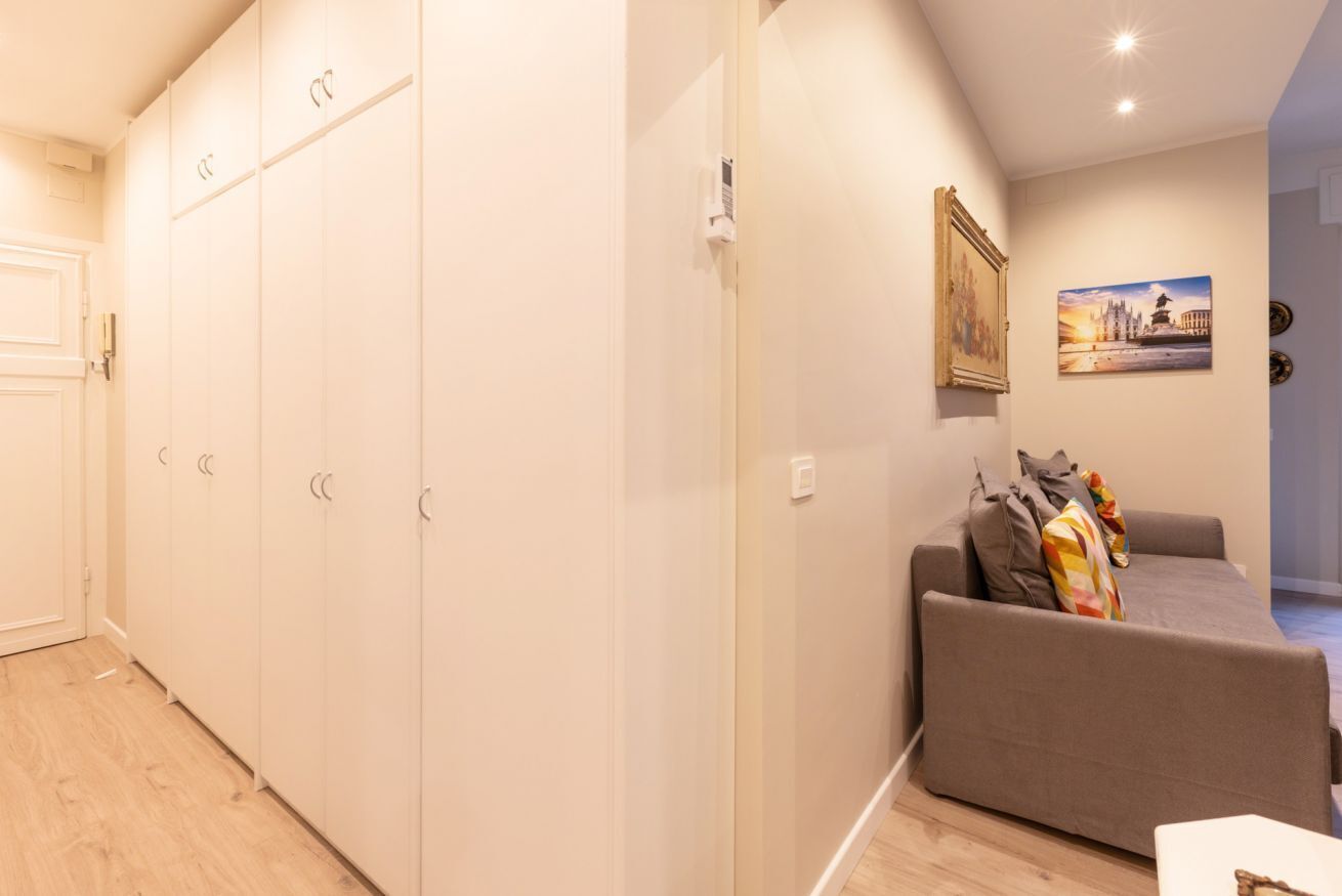 Una habitación con un sofá gris, un armario blanco y un cuadro en la pared.