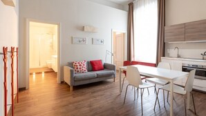 Apartamento moderno con comedor, kitchenette y un baño visible a través de una puerta abierta.