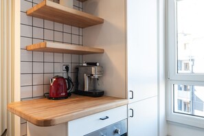 A kitchen with wooden shelves, a coffee maker, and a kettle.