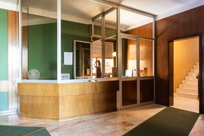 A reception area with a wooden counter, glass doors, and a staircase to the right.