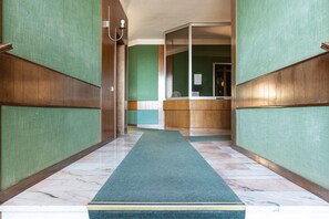 A hallway with a green carpet, wooden paneling, and a reception desk. - Modern one bedroom Navigli - Mirable PM (Milano)