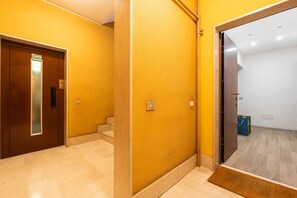 Un couloir avec une porte d’ascenseur marron, un mur jaune et un plancher en bois.