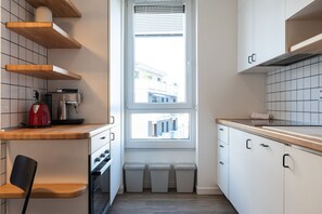 A compact kitchen with white cabinets, a wooden countertop, a red kettle, and a window with blinds. - Modern one bedroom Navigli - Mirable PM (Milano)