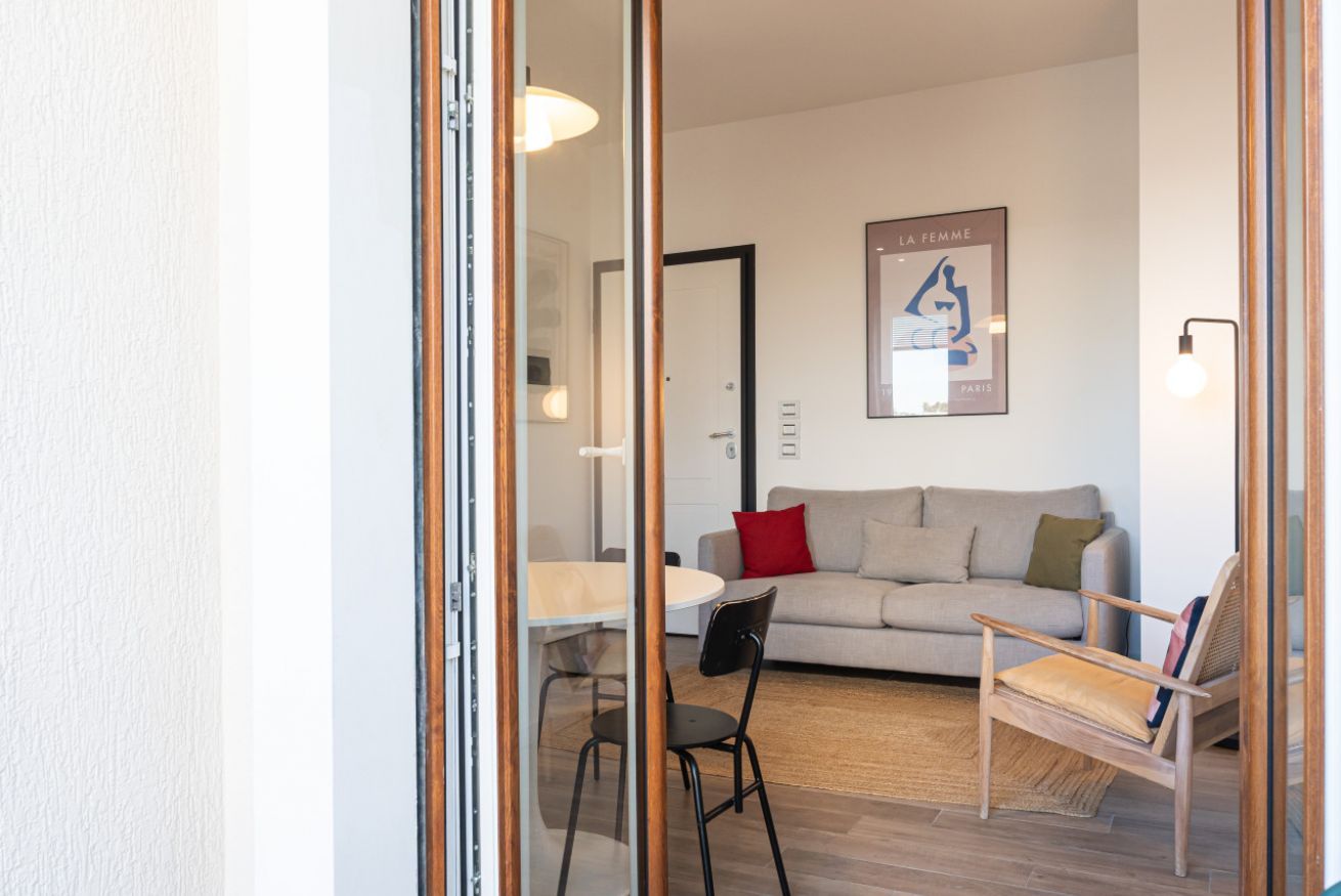A modern living room with a sofa, a chair, a table, and a framed artwork on the wall.