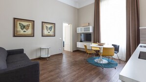 A modern living room with a sofa, a dining area with a table and chairs, and two framed butterfly pictures on the wall. - one bedroom 1st floor - Mirable PM (Milano)