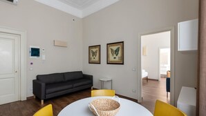 A modern living room with a dark grey sofa, a round white table with a woven basket, and two framed butterfly pictures on the wall. - one bedroom 1st floor - Mirable PM (Milano)