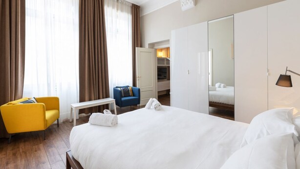 A hotel room with a large bed, a desk, a chair, a wardrobe, and a mirror. - one bedroom 1st floor - Mirable PM (Milano)