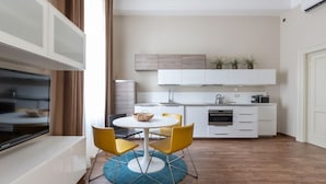A modern kitchen with white cabinets, a built-in oven, and a dining area with a round table and yellow chairs. - one bedroom 1st floor - Mirable PM (Milano)
