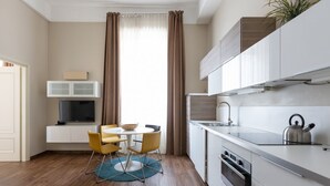 A modern kitchen with white cabinets, a built-in oven, and a kettle on the counter. - one bedroom 1st floor - Mirable PM (Milano)