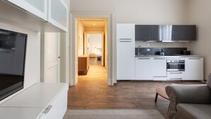 A modern kitchen with white cabinets, a built-in oven, and a stainless steel range hood.