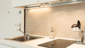 A modern kitchen with two stainless steel sinks, a glass soap dispenser, and a black induction cooktop. - Charmant onebedroom Isola A (Milano)