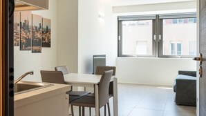 A modern kitchen with a dining area, a large window with a city view, and a small seating area. - Charmant onebedroom Isola A (Milano)