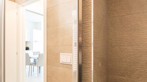 A hallway with beige walls and a door leading to a dining area with white chairs and a table.