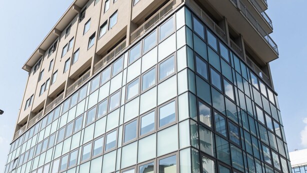 A multi-story building with a modern glass facade and balconies on the upper floors.