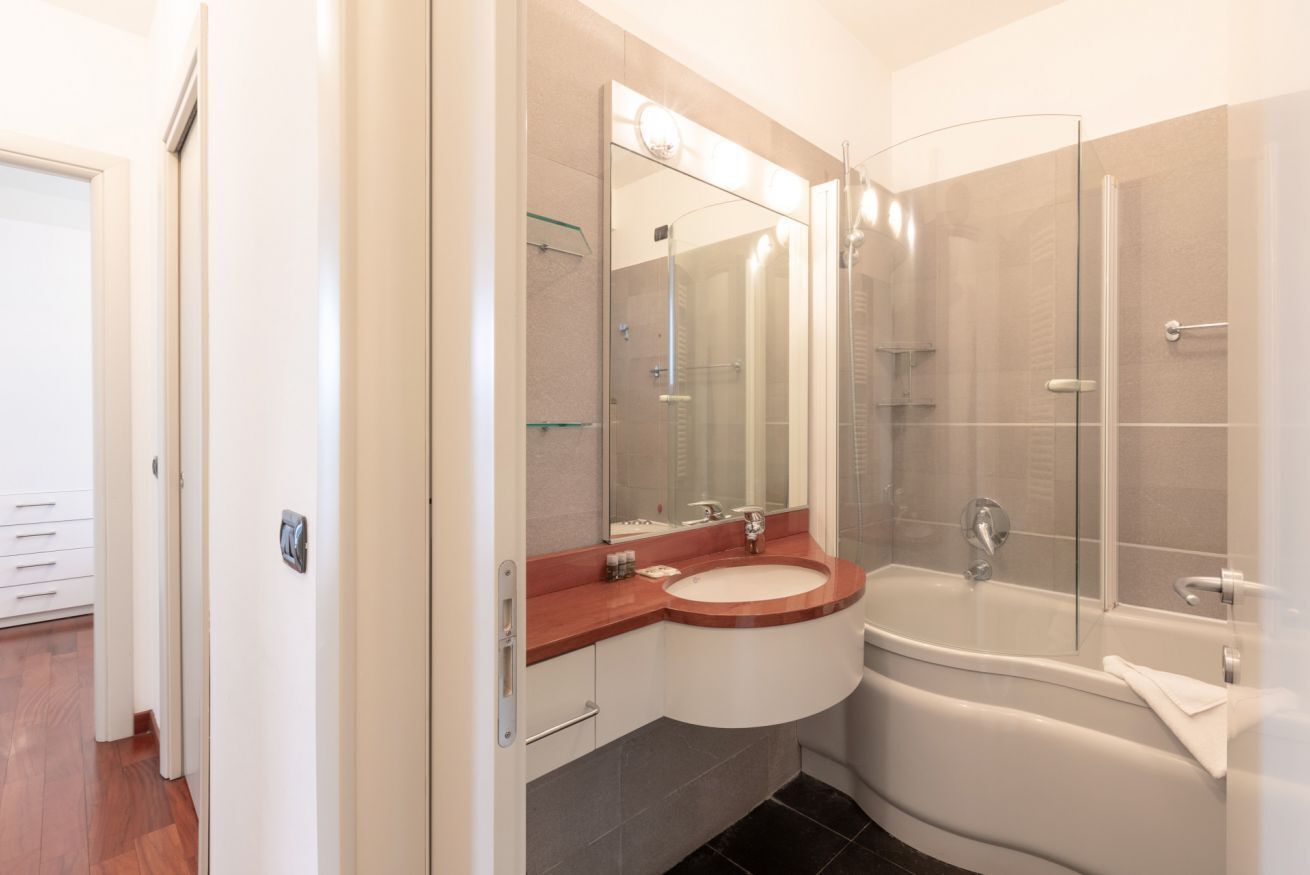 A modern bathroom with a glass shower enclosure, a white sink, and a freestanding bathtub.