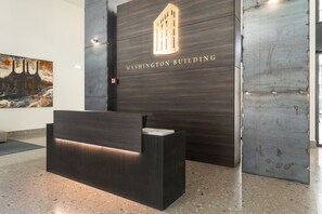 Ein Empfangsschalter im modernen Design, eine große Wand mit dem Schriftzug "WASHINGTON BUILDING" und ein Fenster, sowie ein Gemälde an der Wand.