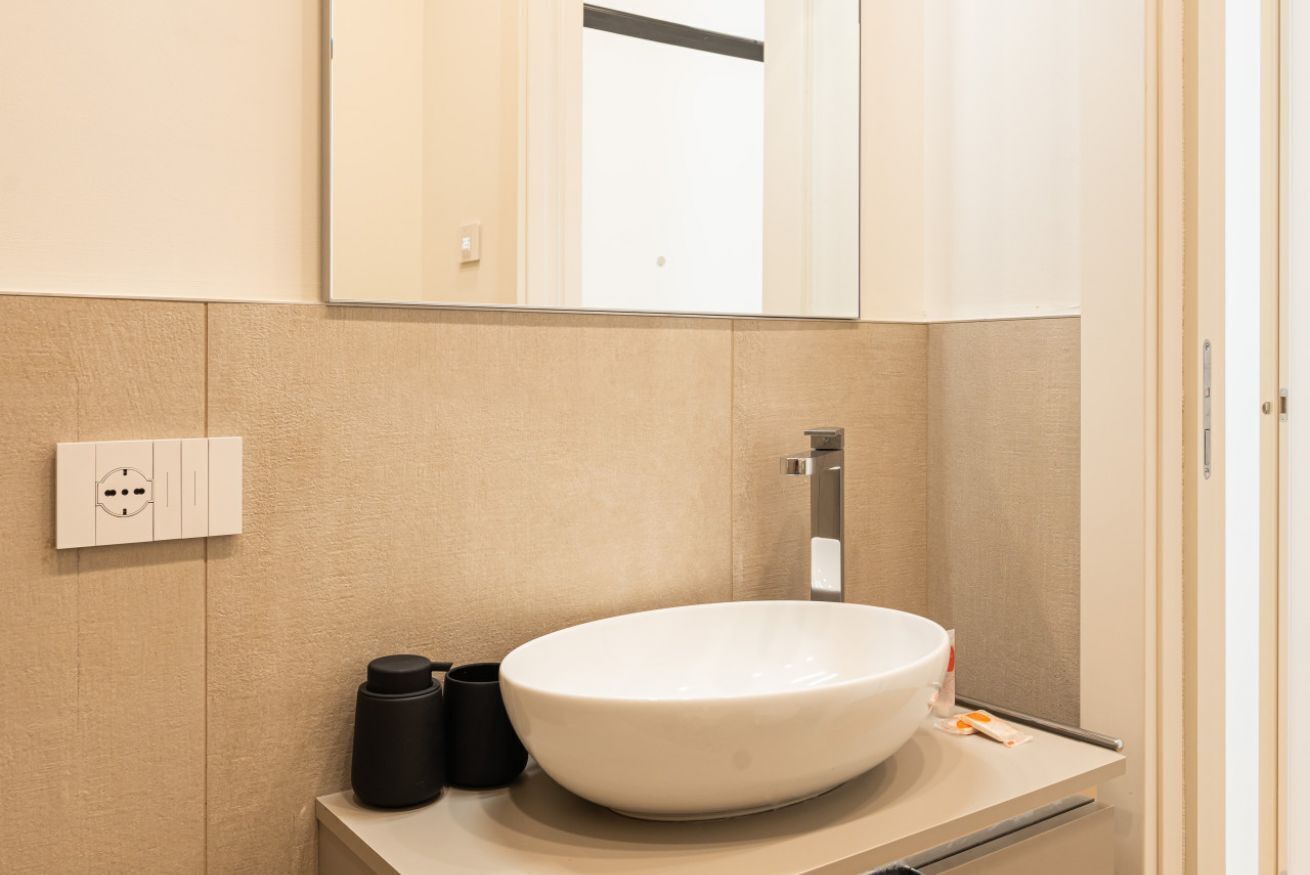 Une salle de bain moderne avec un grand lavabo blanc, un miroir au-dessus et un porte-serviettes sur le côté gauche.