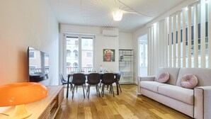 Una sala de estar moderna con sofá, mesa de comedor, sillas y televisor.