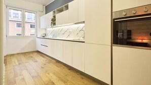 Una cocina moderna con armarios blancos, encimera de mármol y horno empotrado.
