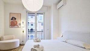 Una habitación de hotel moderna con una cama grande, un área de descanso circular y un balcón con vista a la ciudad.