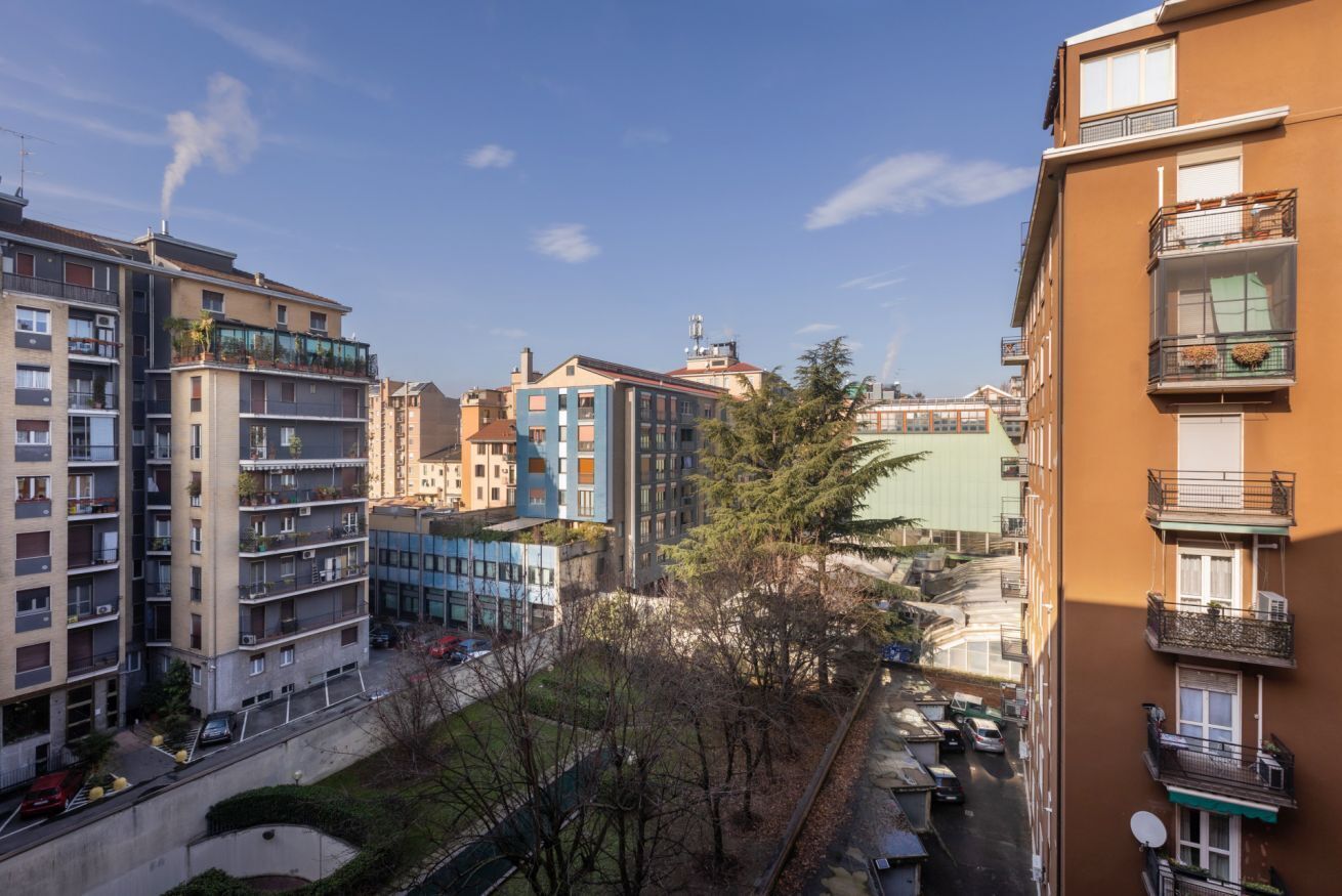 A residential area with multi-story buildings, balconies, and a clear sky.
