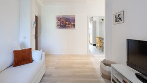 A modern living room with a sofa, a television, and a painting on the wall.