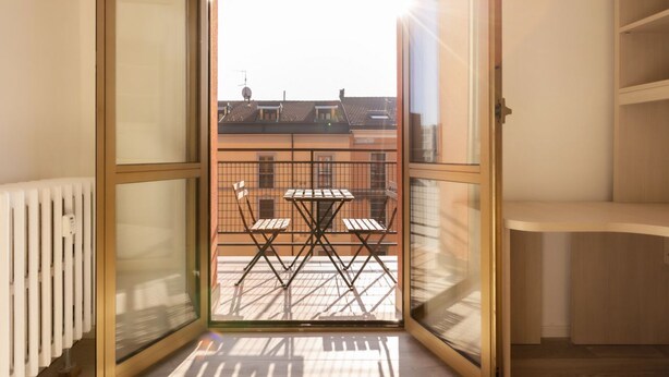 A balcony with a table and chairs, a view of buildings, and a radiator.