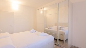 A modern hotel room with a large bed, a walk-in closet, and a mirror.