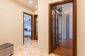 A hallway with a wooden door leading to a room with a bed and a TV. - Three Bedrooms Rovereto 1° floor - Mirable PM (Milano)