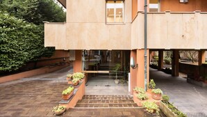 Un edificio con techo plano, entrada de vidrio y macetas dispuestas en filas.