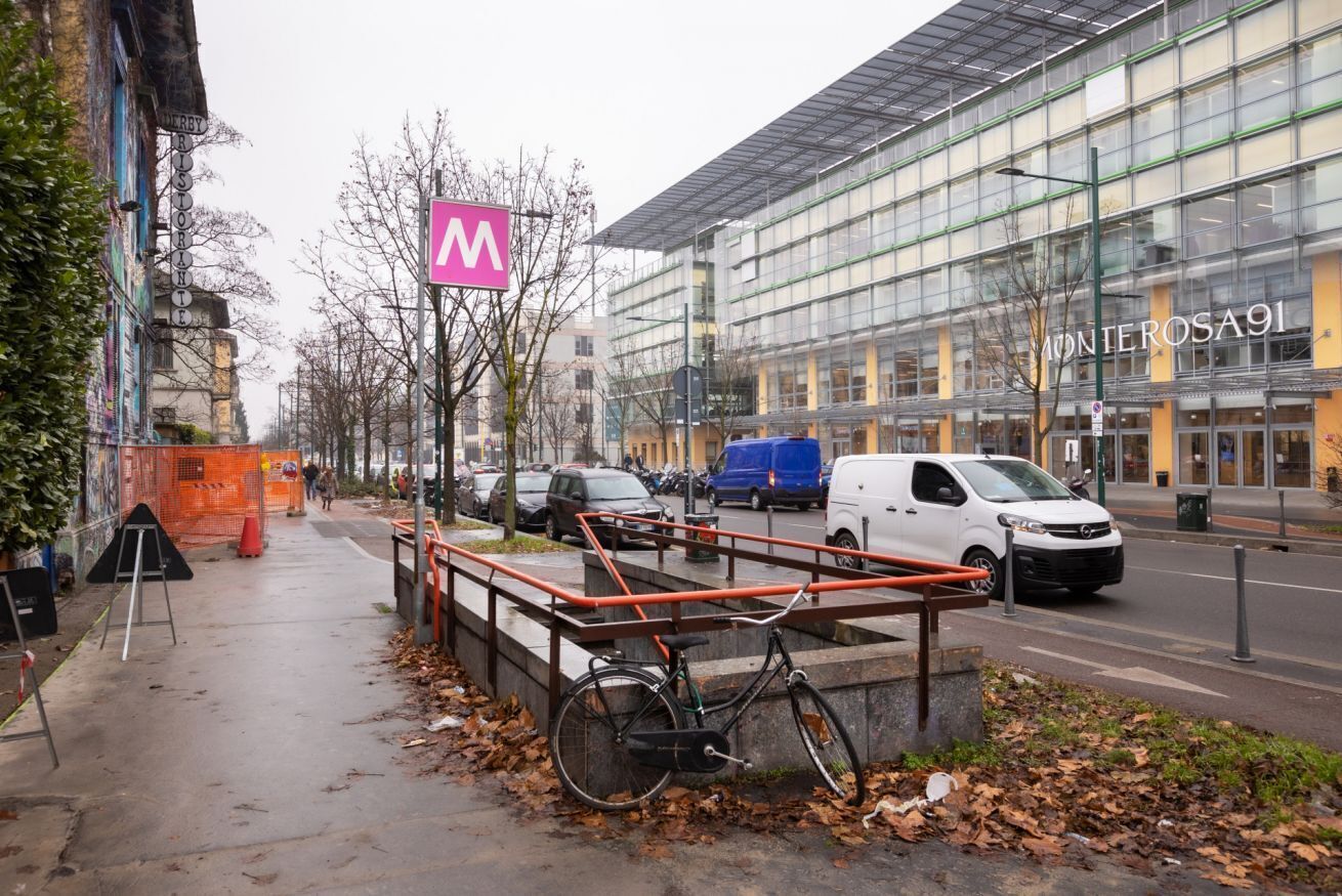 Un bâtiment moderne à la façade vitrée, avec un vélo garé devant et un passage piétonnier.