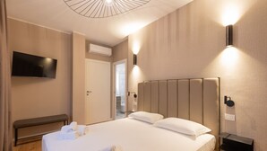 Habitación de hotel con una cama grande, un televisor de pantalla plana en la pared y una mesita de noche con lámpara.