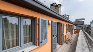 Een woongebouw met grote ramen, luiken en een balkon met een tafel en stoelen.