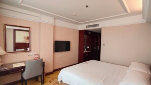 A hotel room with a bed, a desk with a chair, a television, and a mirror. - VN hotel -Guangdong Heyuan Hongxing road (Heyuan)