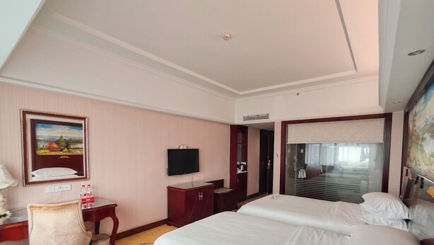 A hotel room with two beds, a desk with a chair, a television, and a painting on the wall. - VN hotel -Guangdong Heyuan Hongxing road (Heyuan)