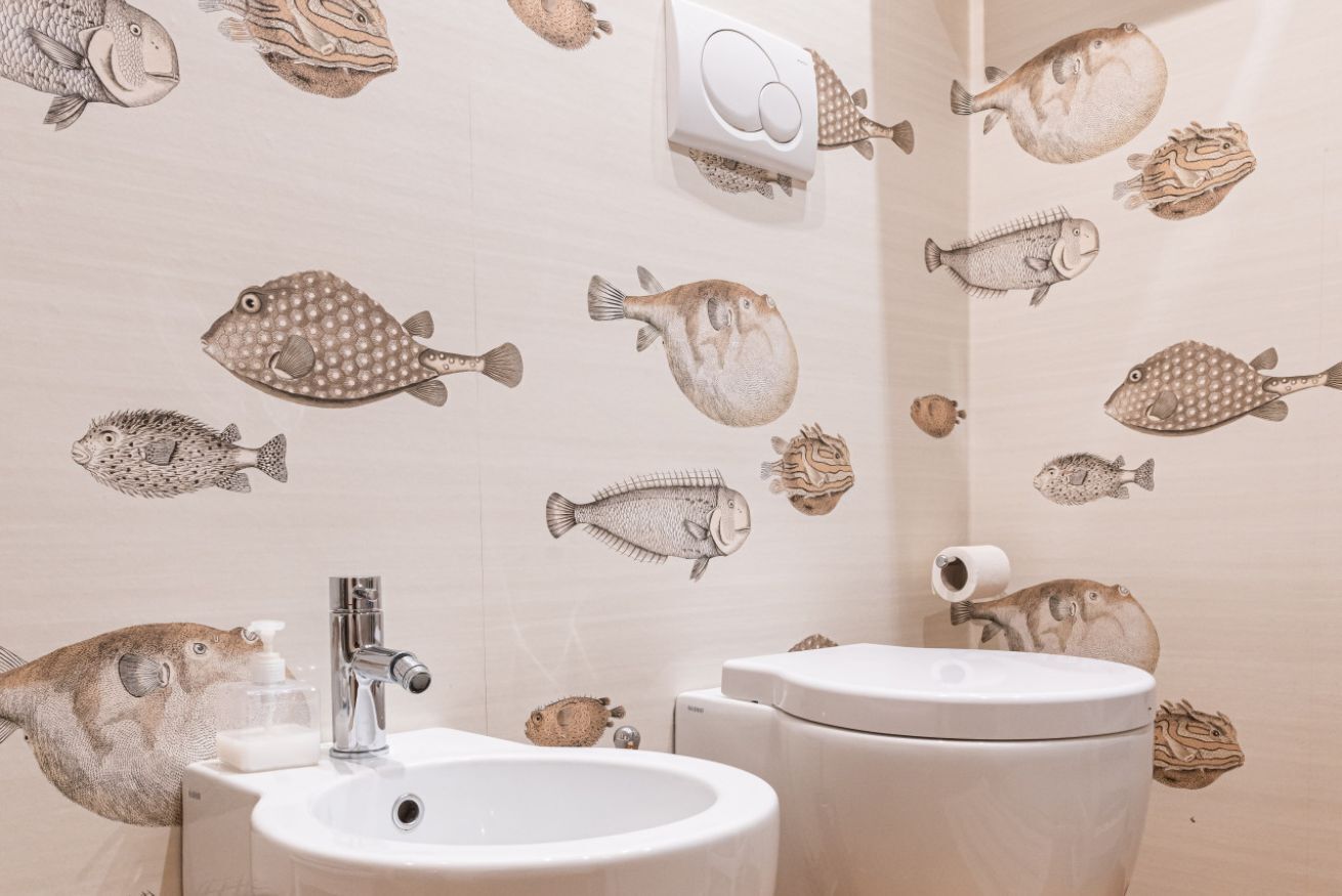 Een badkamer met een wastafel en toilet, versierd met visstickers op de muur.