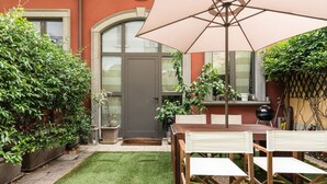 Una veranda con tavolo e sedie, un ombrellone grande e una porta che dà su una zona coperta.