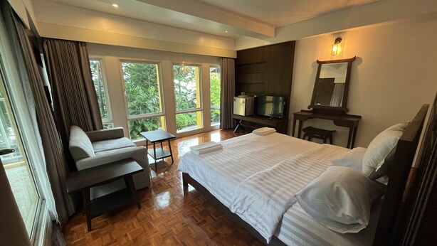 A modern hotel room with a large bed, a sofa, a TV, and a small table. - The Ocean Private beach (Pattaya)