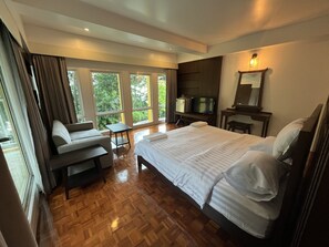 Una habitación de hotel moderna con una cama grande, un sofá, un televisor y una mesita.