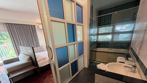 A modern bathroom with a glass shower enclosure, a bathtub, and a sink with a black countertop. - The Ocean Private beach (Pattaya)