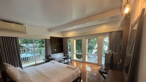 A hotel room with a bed, a desk, a chair, and large windows offering a view of the outdoors. - The Ocean Private beach (Pattaya)