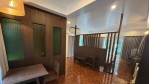 A spacious room with a wooden parquet floor, a dining table with chairs, and a large window with curtains. - The Ocean Private beach (Pattaya)