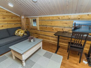 Et hyggeligt sommerhusinteriør med sofa, bord og stol.