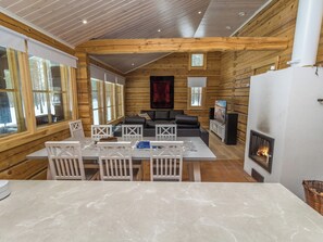 L’intérieur d’une cabane en rondins comprend un coin repas, des sièges et une cheminée.