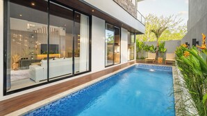 Una casa moderna con piscina, amplios ventanales y un jardín cuidado.