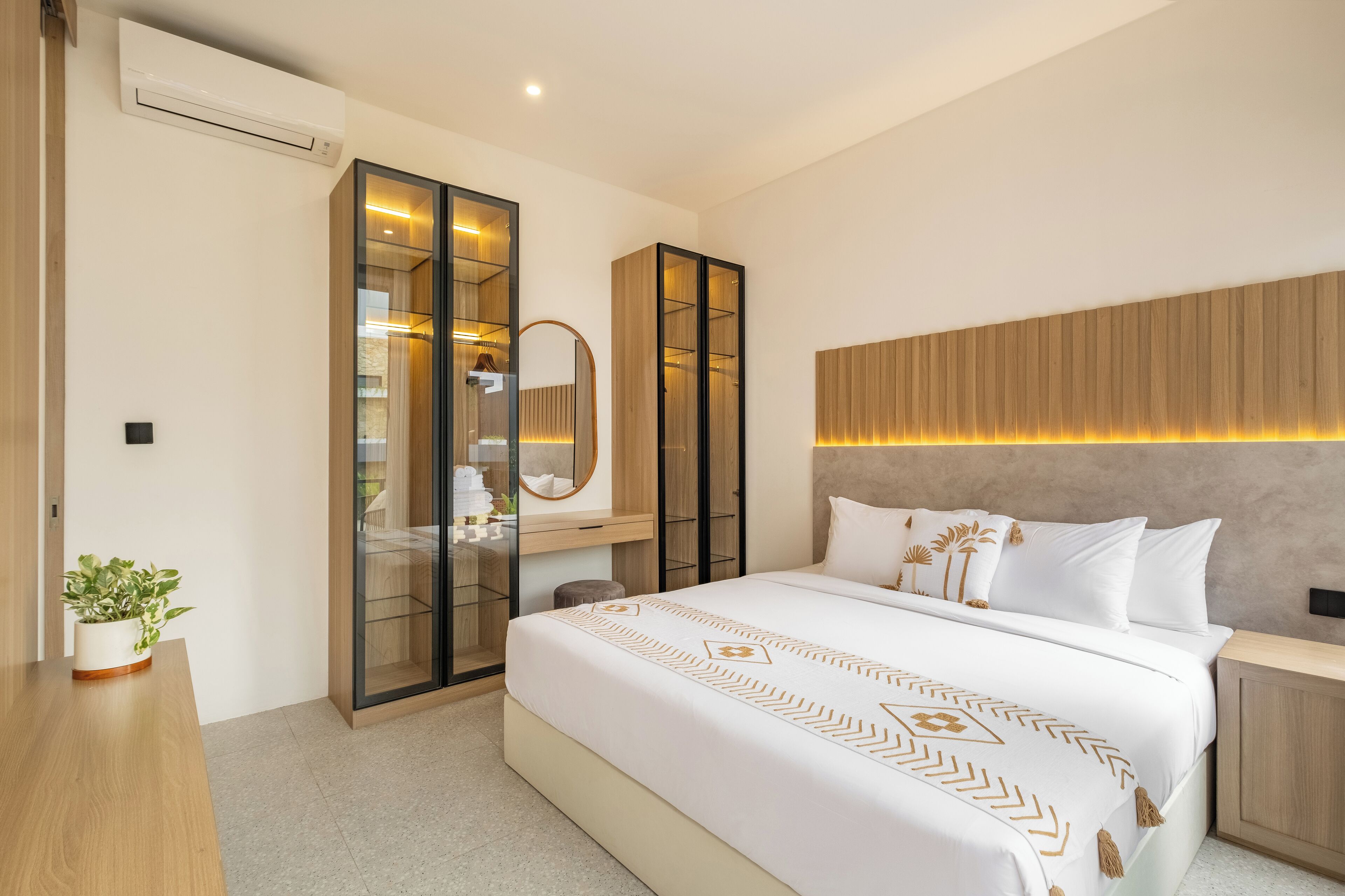 A modern bedroom with a large bed, built-in wardrobe, and a bedside table.
